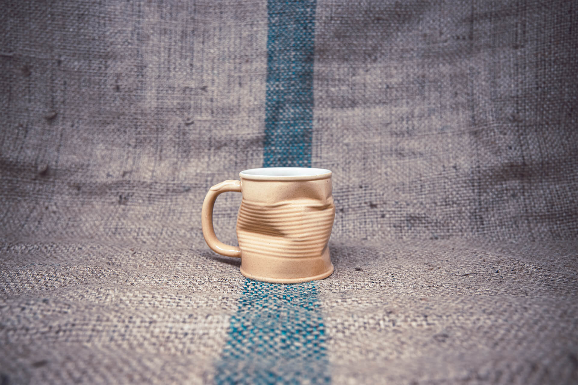 Reusable ceramic coffee cup designed to look like a crumpled cardboard takeaway cup